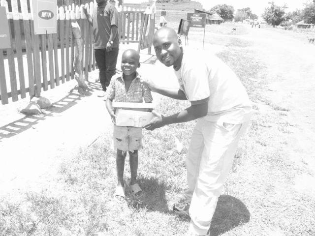 Seggy hands a box of soap to a little one Seggy hands a box of soap to a little one